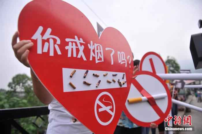 5月30日，重庆涪陵红酒小镇景区的工作人员拿着写有“你戒烟了吗”桃心形状牌要求游客灭掉手中的香烟，迎世界无烟日。陈超 摄